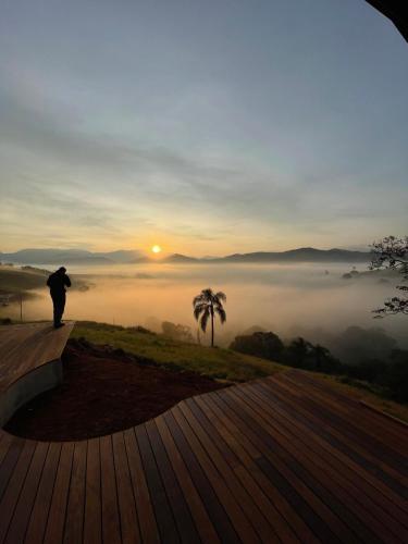 a person standing on a deck watching the sunrise at Refúgio Terras Altas in Itanhandu