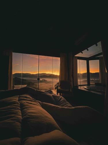 a bed in a bedroom with a view of the sunset at Refúgio Terras Altas in Itanhandu