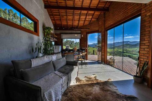 a living room with a couch and large windows at Refúgio Terras Altas in Itanhandu