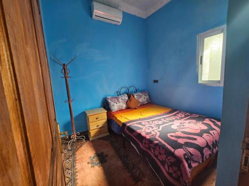 a bedroom with a bed in a blue room at Merzouga Quiet apart &camels trecking in Merzouga
