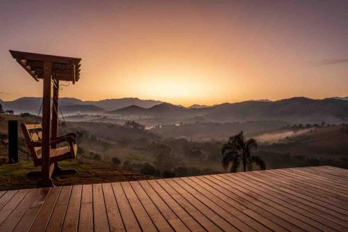 a bench on a wooden deck with a view of a mountain at Refúgio Terras Altas in Itanhandu