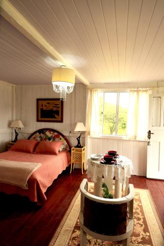 a bedroom with a bed and a table in it at Chalé dos Sonhos e Encantos em Monjolinho in Ponte Alta