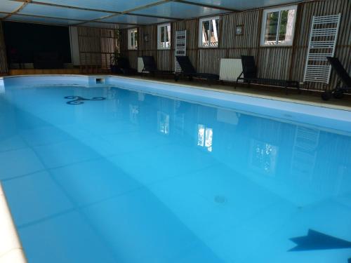 une grande piscine avec de l'eau bleue dans l'établissement Country home with indoor pool 20 pers, à Cléguérec