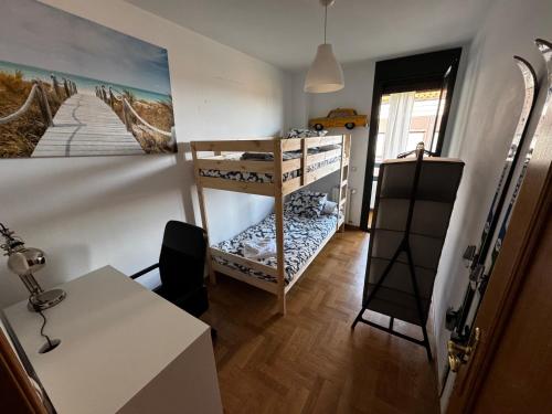 une chambre avec des lits superposés, un bureau et une table dans l'établissement El Rincón del Reloj, à Llanes