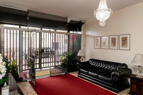 uma sala de estar com um sofá de couro preto e um tapete vermelho em Copacabana ampla vista mar no Rio de Janeiro