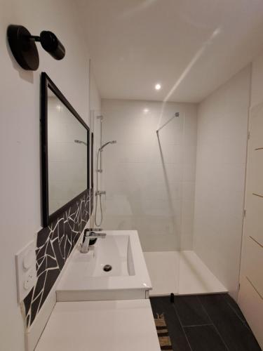 une salle de bain blanche avec un lavabo et un miroir dans l'établissement Chambre côté terrasse, à Maureillas