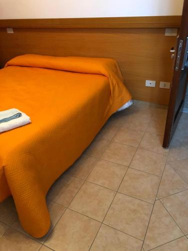 an orange bed in a room with a tile floor at Albergo BELVEDERE in Santa Cristina Gela