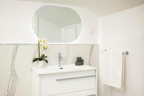 a white bathroom with a sink and a mirror at Panoramic Attic by Sabugo House in Relógio do Poiso