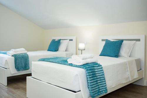 two white beds with blue pillows in a room at Panoramic Attic by Sabugo House in Relógio do Poiso