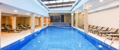 a pool in a hotel with chairs and tables at Predela 2 Aparthotel in Bansko