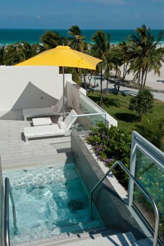 a pool with an umbrella and a bench and a beach at Leslie Hotel Ocean Drive in Miami Beach