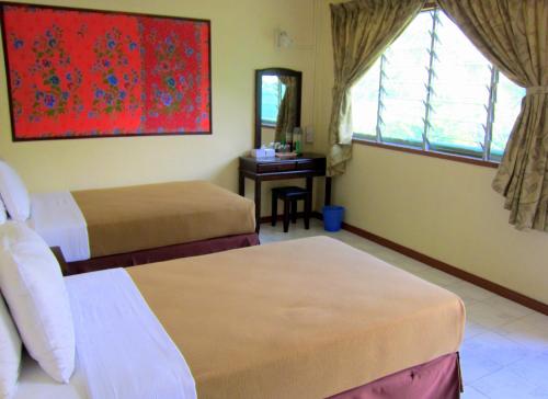a hotel room with two beds and a desk at Mile 36 Lodge in Kundasang