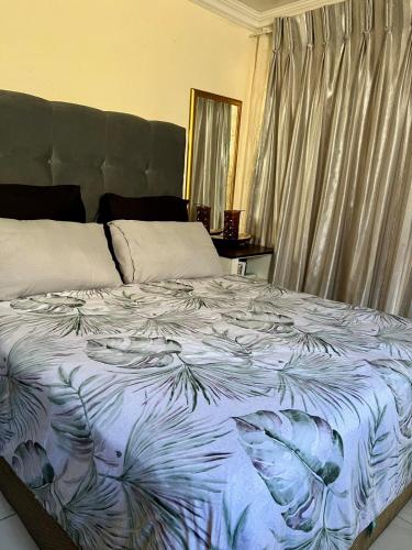 a bed with a blue and white comforter on it at The Ripanga Nest in Nelspruit