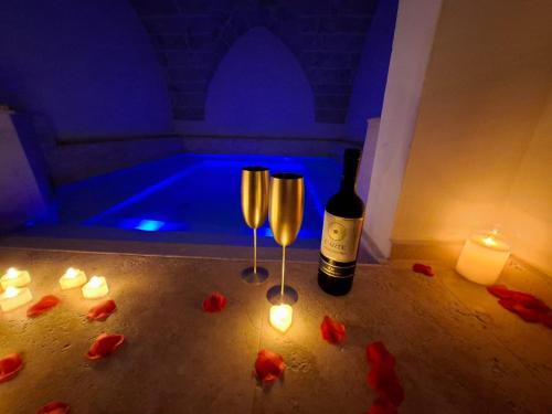 a bottle of wine and two glasses in a room with candles at Zahra Superior Suite with private pool in Sannicola