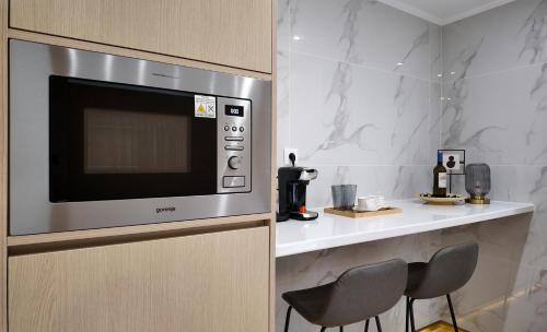 a kitchen with a microwave and a counter with chairs at CC LUX Suites in Piraeus