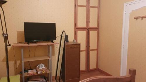 une chambre avec une télévision sur une table et une étagère dans l'établissement L'ébène - Chez L'habitant, à Château-du-Loir