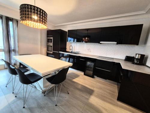 d'une cuisine avec une table, des armoires noires et un lustre. dans l'établissement Résidence Le Constellation - Logement spacieux au coeur ville d'Aix les Bains ! MAE-6394, à Aix-les-Bains