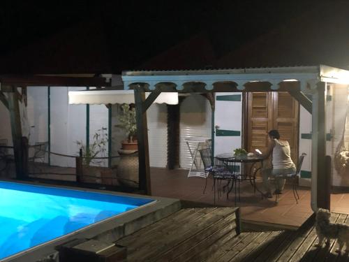 a woman sitting at a table next to a swimming pool at Aichi's lodges -gîtes in Capesterre-de-Marie-Galante
