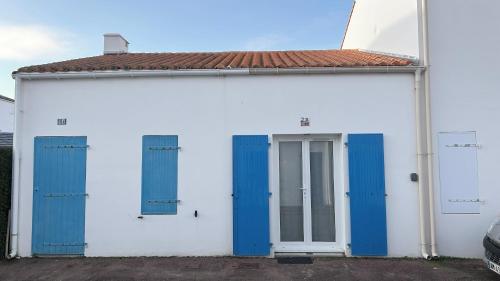 un edificio bianco e blu con porte blu di L'Atlantide Maison & Spa - Accès direct à la plage a Saint-Hilaire-de-Riez
