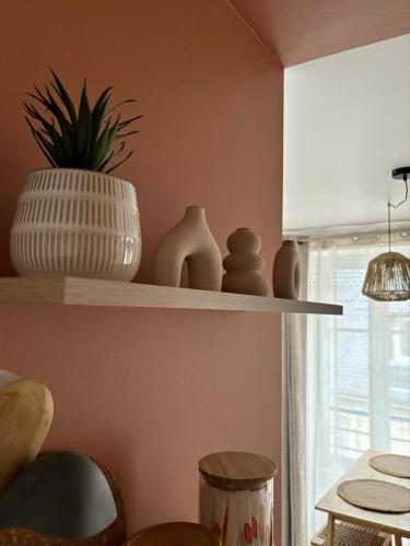 a shelf with pots and vases on it in a room at Cocon du Berry cœur historique in Bourges
