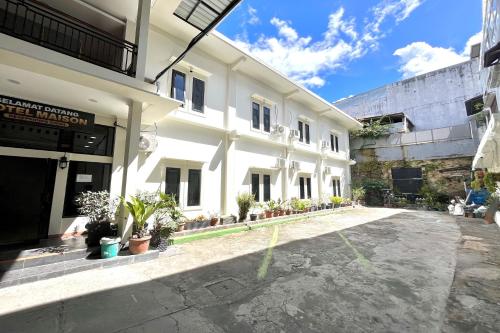 a large white building with potted plants in a courtyard at Maison Hotel Bukittinggi in Bukittinggi