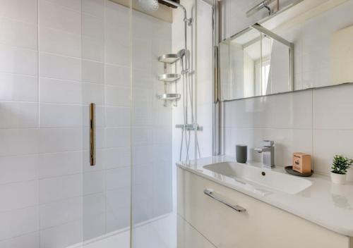 une salle de bain blanche avec un lavabo et un miroir dans l'établissement Typical & Charming flat near St Germain - Mid-term, à Paris