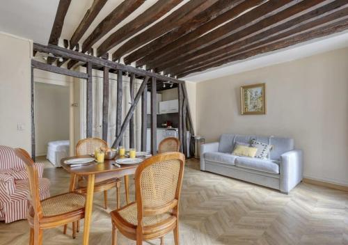 un salon avec une table, des chaises et un canapé dans l'établissement Typical & Charming flat near St Germain - Mid-term, à Paris