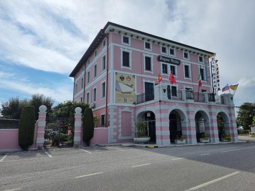 a pink building with a clock on the side of it at Dogana Vecchia - Hotel & Residence B&B Ristorante & Pizzeria in Trivignano Udinese