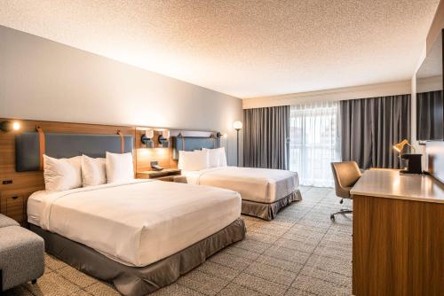 a hotel room with two beds and a desk at Sonesta Select Dallas Richardson in Richardson