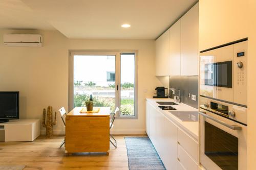 a kitchen with white cabinets and a large window at Luxury Refuge - Seixal Bay in Seixal