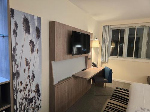 a hotel room with a desk and a television at Novotel Nottingham Derby in Long Eaton