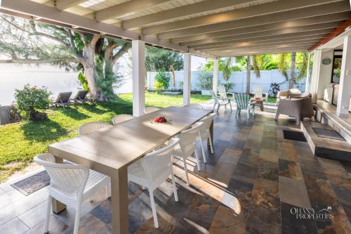 a wooden table and chairs on a patio with a tree at Villa Vanaki - Beachfront Villa 4BR w AC in Moorea