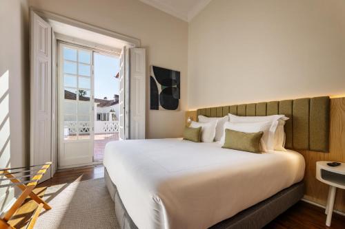 a bedroom with a large white bed and a window at CICIOSO boutique hotel in Évora