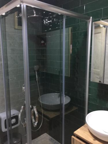 a green tiled bathroom with a shower and a sink at Parla dağ evi kırmızı oda in Çamlıhemşin
