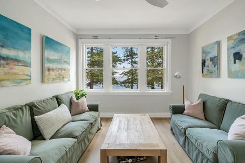 a living room with two green couches and a table at Renovated Harbourfront Home With Harbour Views in Sydney