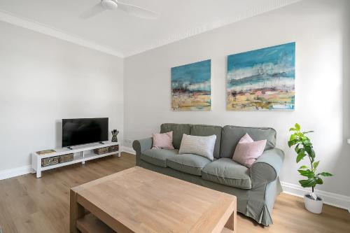a living room with a couch and a tv at Renovated Harbourfront Home With Harbour Views in Sydney