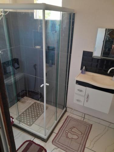 una ducha con puerta de cristal en un baño en Quintal Compartilhado - Casa Temporada, en Armacao dos Buzios