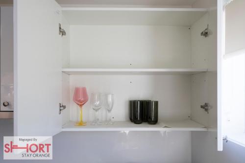 a white shelf with two glasses and a wine glass at Conservatorium Villa 1 in Orange