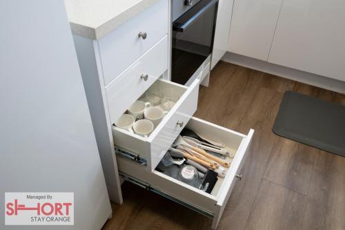 a kitchen cabinet with a drawer filled with cooking utensils at Conservatorium Villa 1 in Orange