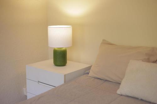 a lamp on a night stand next to a bed at Quarto Casal com Varanda Casa Caramel in Belo Horizonte