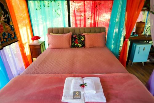 a bedroom with a bed with two towels on it at Nirvana Glamping, Nature Glass Chalet in São Francisco Xavier