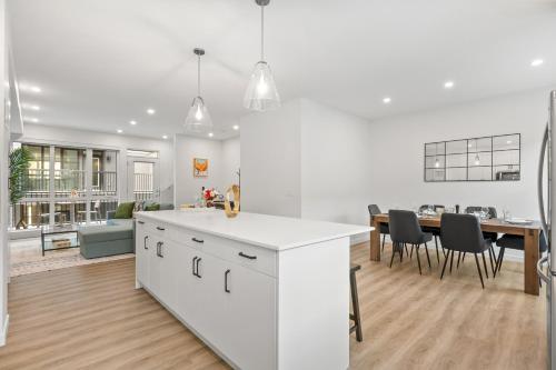 a white kitchen and dining room with a dining table at Luxury 3 Bedrooms Spacious Townhome, 2 Car Garage, Sleeps 8, Heater & AC, King Bed, Easy Ski Access, Next to WinSport, 10km from Calgary Downtown, Near Banff in Calgary