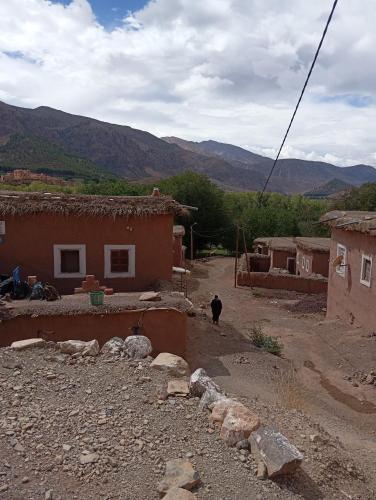 a person walking down a dirt road next to houses at Gite Timit la maison Imazghn in Azilal