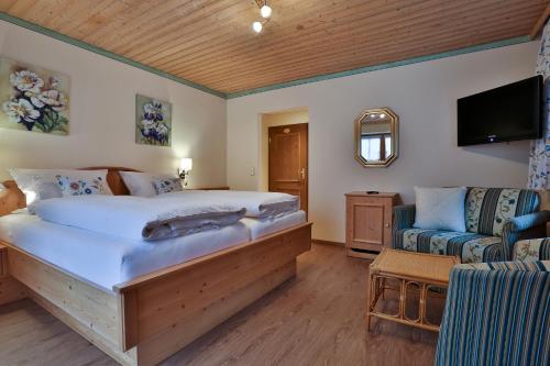 a bedroom with a large bed and a chair at Gästehaus Alexandra in Ramsau