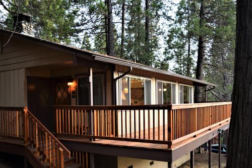 a house with a large deck in the woods at Sequoia House at The Redwoods in Wawona