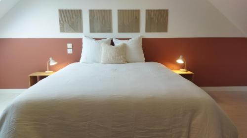 a bedroom with a large white bed with two lamps at November Charlie, appartement en centre ville de Bruz in Bruz