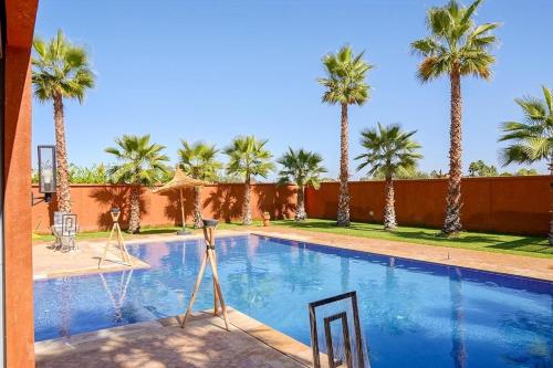 a swimming pool with palm trees in the background at VILLA NOÛR PALACE avec piscine jaccuzi à Marrakech in Marrakech