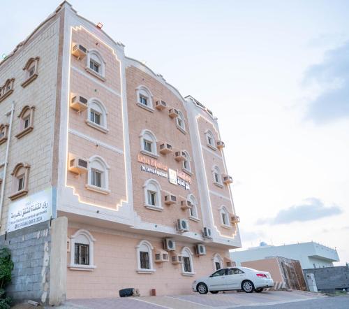 a building with a car parked in front of it at رؤى القنفذة للشقق المخدومة in Al Qunfudhah