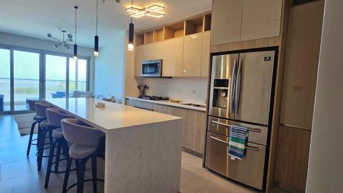 a kitchen with a refrigerator and a counter with bar stools at Playa Escondida in María Chiquita