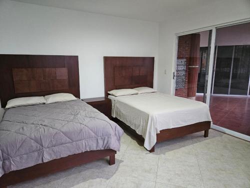 ein Schlafzimmer mit zwei Betten und einem Fenster in der Unterkunft Casa El Mirador - Burgos, Familiar in Temixco